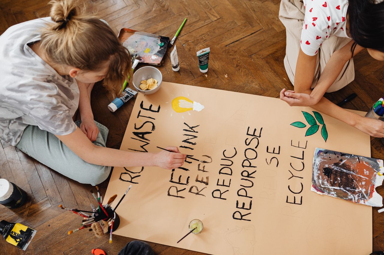 Crafting Captivating Headlines: Your awesome post title goes here Top view of two young adults crafting an eco-friendly sign emphasizing recycling and repurposing.